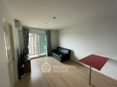 Spacious and bright living room with large windows leading to a balcony, featuring a sleek black sofa and a minimalist design, perfect for modern living.