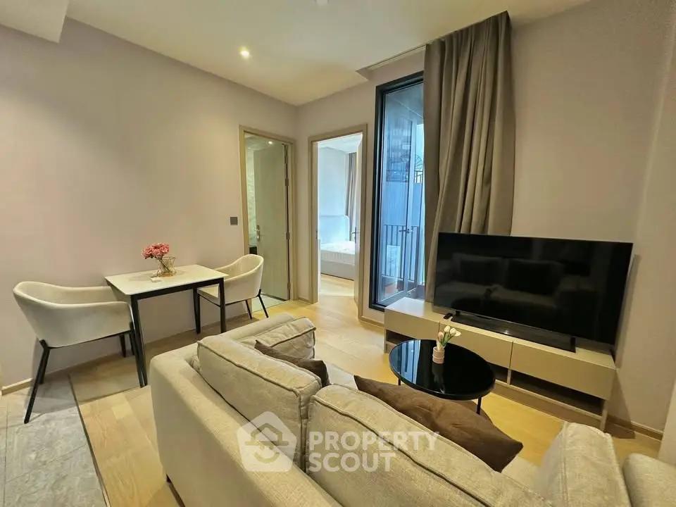 Modern living room with cozy seating and large TV, adjacent to dining area and bedroom.