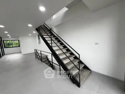 Modern open-plan interior with sleek staircase and large windows