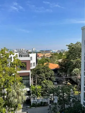 Stunning cityscape view from a high-rise apartment balcony with lush greenery and clear blue skies.