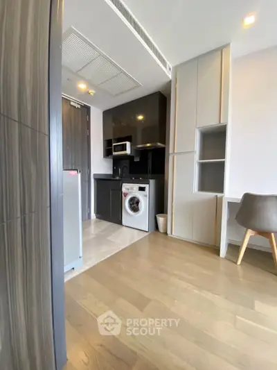 Modern kitchen with sleek cabinetry and built-in washing machine in stylish apartment.