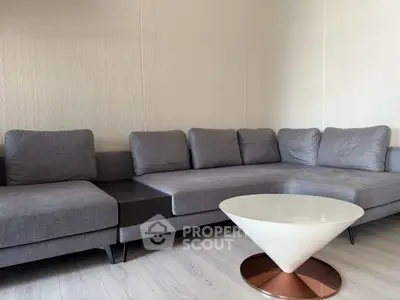 Modern living room with stylish gray sectional sofa and unique white coffee table.