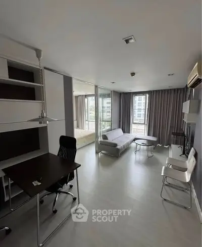 Modern open-plan living room with study area and large windows in urban apartment.