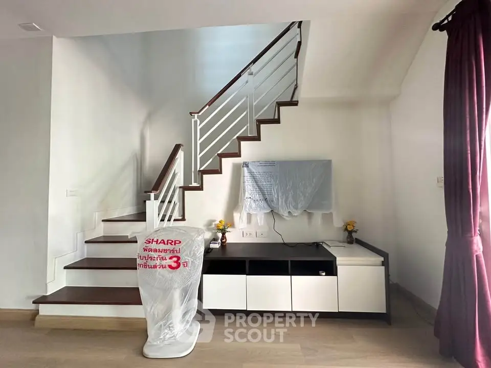 Modern living room with stylish staircase and sleek entertainment unit, perfect for contemporary living.