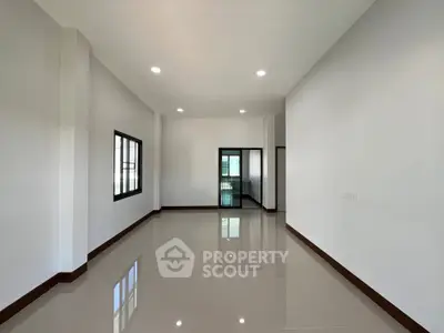 Spacious empty room with glossy tiled floors and large windows, perfect for customization.