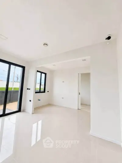 Bright and spacious modern living room with large windows and sleek tile flooring.