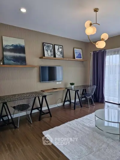 Modern living room with stylish decor, featuring a wall-mounted TV, elegant lighting, and large windows for natural light.
