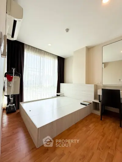 Modern bedroom with wooden flooring and large window for natural light