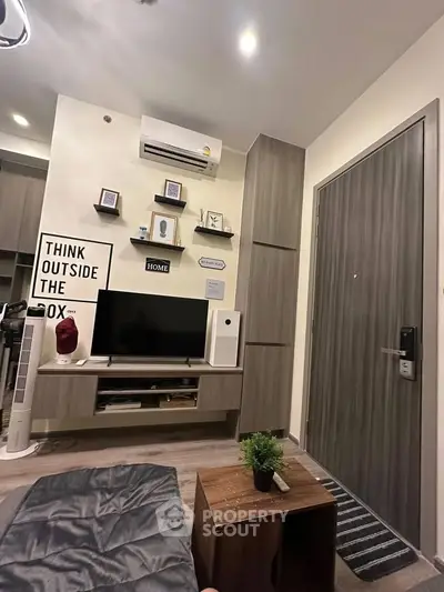 Modern living room with stylish decor and wall-mounted TV in cozy apartment.