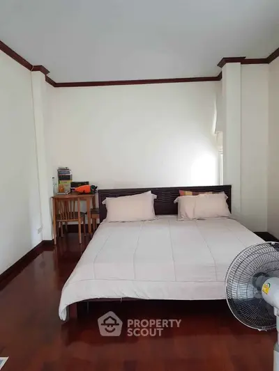 Spacious bedroom with wooden flooring and cozy furnishings in a modern apartment.