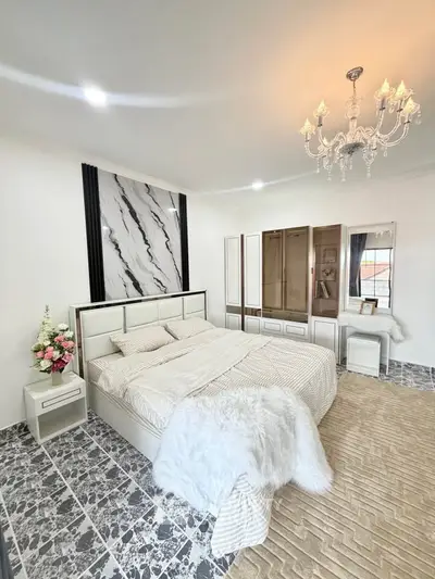 Luxurious bedroom with elegant chandelier and modern decor, featuring a plush bed and stylish flooring.