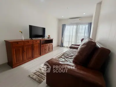 Spacious living room with leather sofa and wooden TV cabinet, bright natural light.