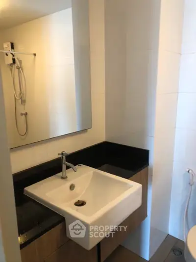 Modern bathroom with sleek sink and shower in contemporary apartment.