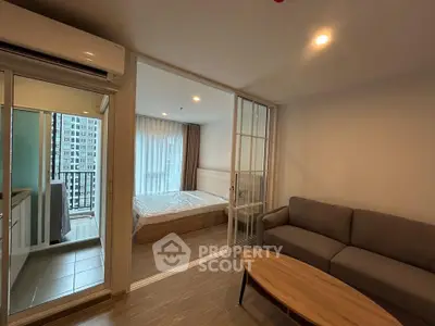Modern apartment interior with cozy living room and bedroom, featuring sliding glass doors and natural light.