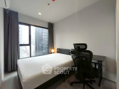 Modern bedroom with city view, featuring a comfortable bed and ergonomic chair.