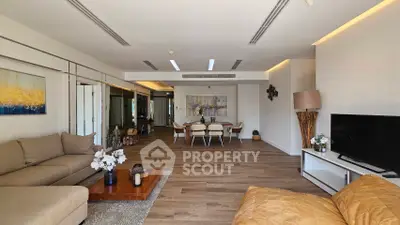 Spacious modern living room with elegant decor and open dining area, featuring stylish furniture and warm lighting.