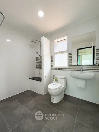 Modern bathroom with sleek fixtures and large tiles, featuring a shower and toilet.