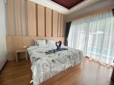 Elegant bedroom with pool view, featuring modern decor and large windows for natural light.