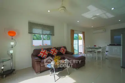 Modern living room with stylish decor and natural light, featuring a cozy sofa and dining area.