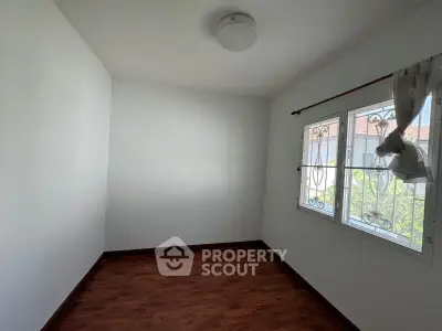 Bright empty room with wooden flooring and large window, perfect for customization.