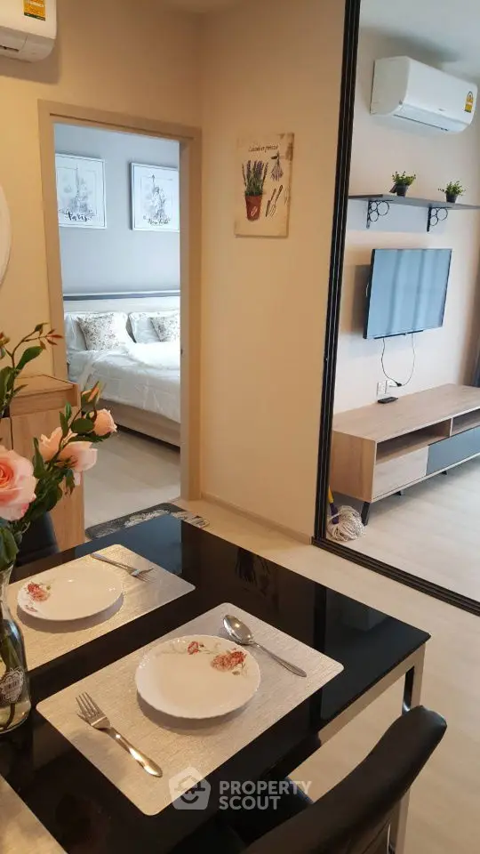 Modern apartment interior with dining area and bedroom view, featuring sleek furniture and decor.