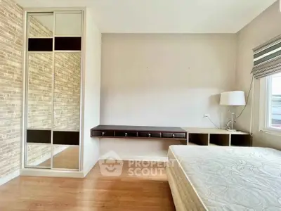 Spacious bedroom with modern design, featuring a mirrored wardrobe and elegant wooden flooring.
