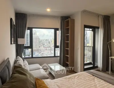 Modern bedroom with city view and cozy seating area in high-rise apartment