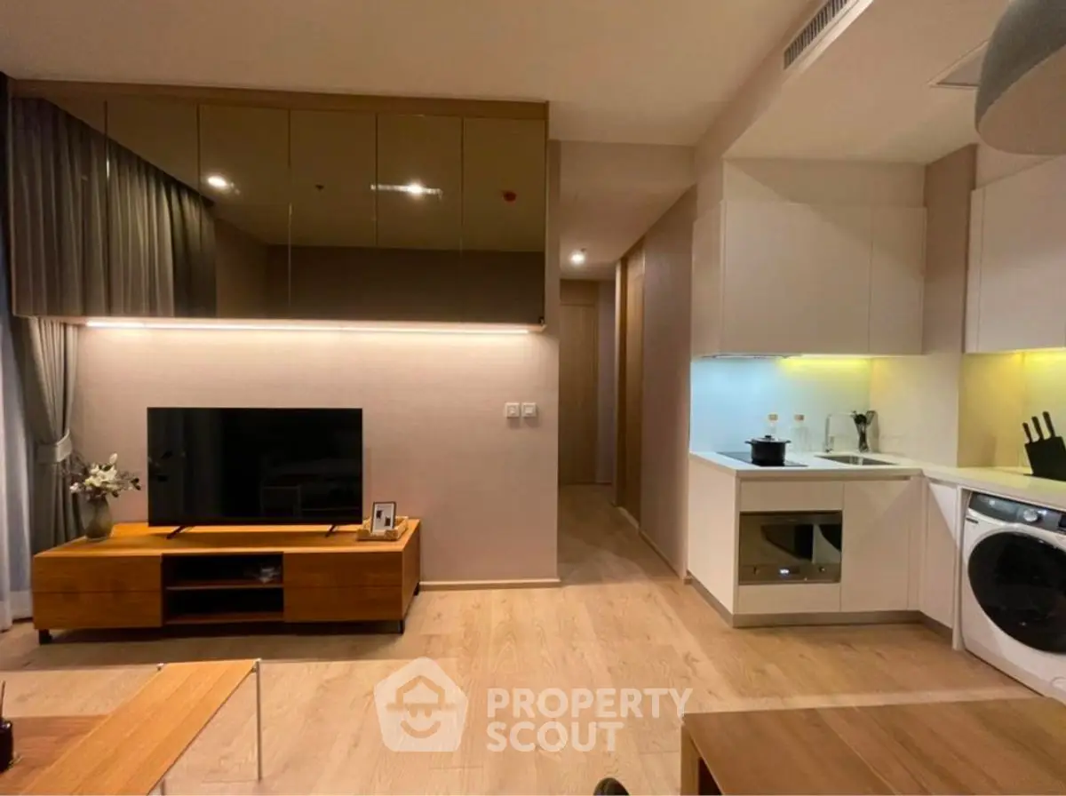 Modern living room with sleek kitchen, wooden floors, and stylish decor