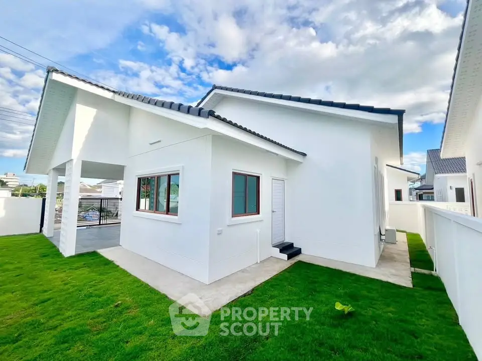 Modern white house with lush green lawn and blue sky backdrop
