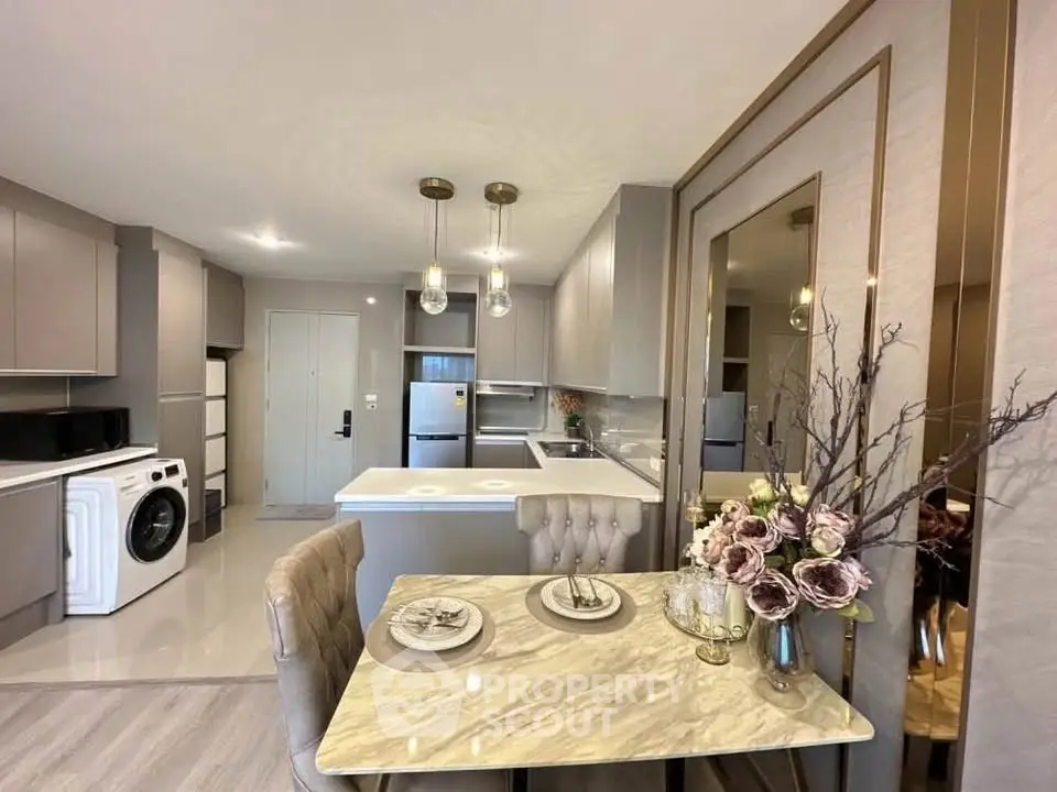 Modern kitchen with elegant dining area and washing machine in stylish apartment