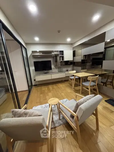 Modern living room with stylish furniture and wooden flooring, featuring a cozy seating area and sleek entertainment unit.