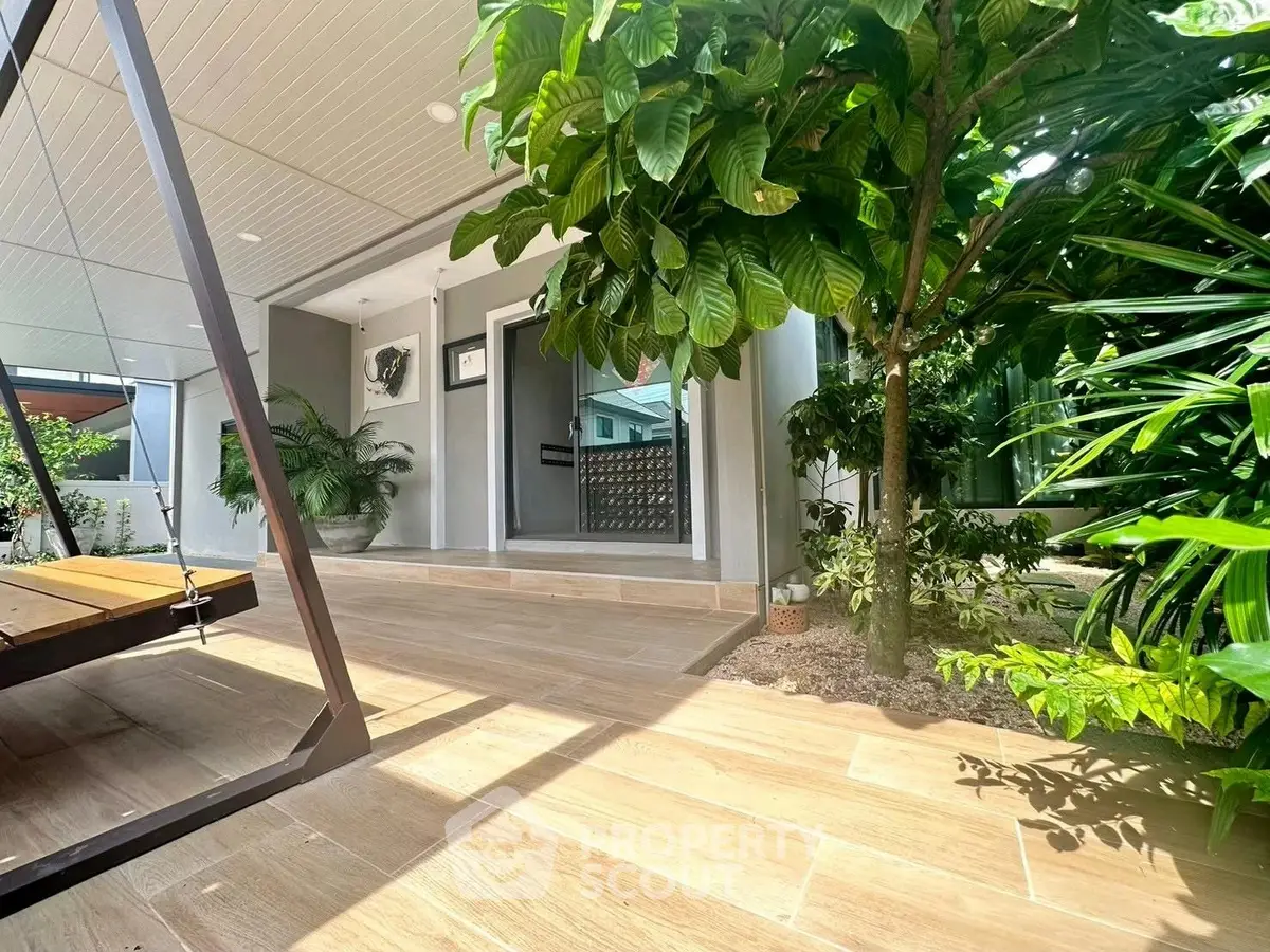 Charming home entrance with lush greenery and modern swing, perfect for relaxation.