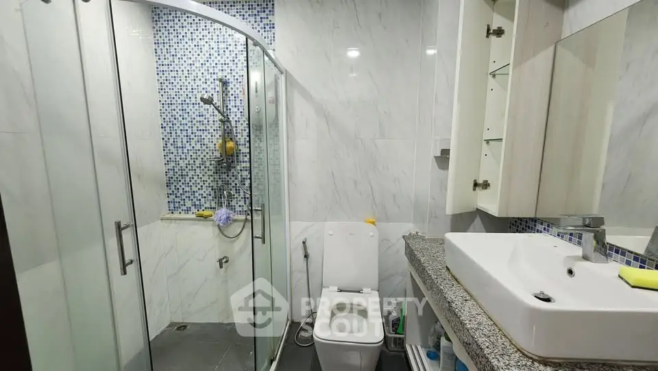 Modern bathroom with glass shower and sleek vanity in a stylish home.