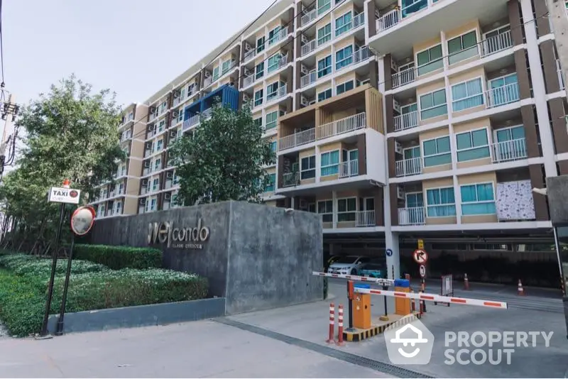 Modern condominium complex entrance showcasing secure access gate, well-maintained facade, and lush greenery, ideal for urban living.