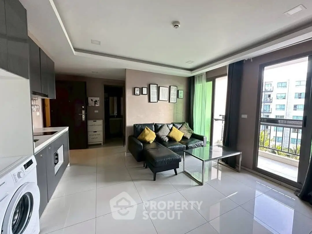 Modern living room with sleek kitchen, large windows, and washing machine in open layout.