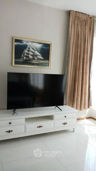 Elegant living room with modern TV setup and nautical artwork, featuring luxurious curtains and glossy flooring.