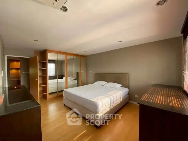 Spacious bedroom with large mirrored wardrobe and natural light