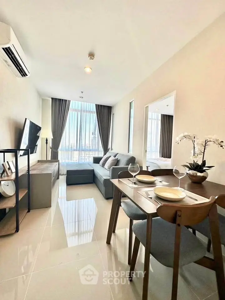 Modern living room with dining area, featuring sleek furniture and large windows for natural light.