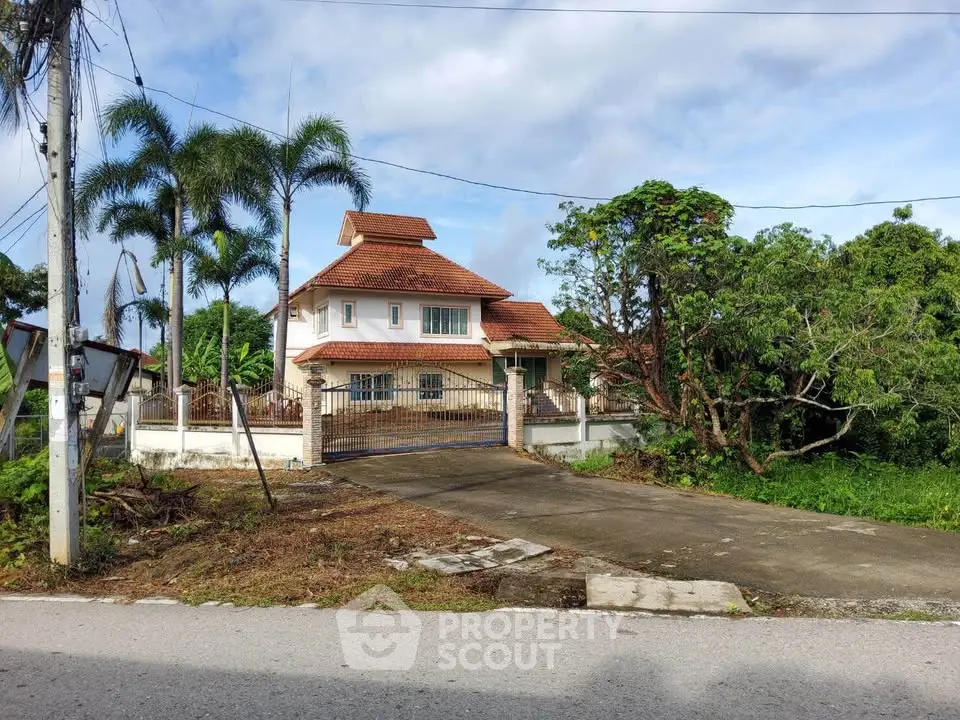 Charming two-story house with red roof and lush greenery, perfect for serene living.