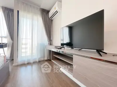 Modern living room with sleek TV setup and large windows for natural light.