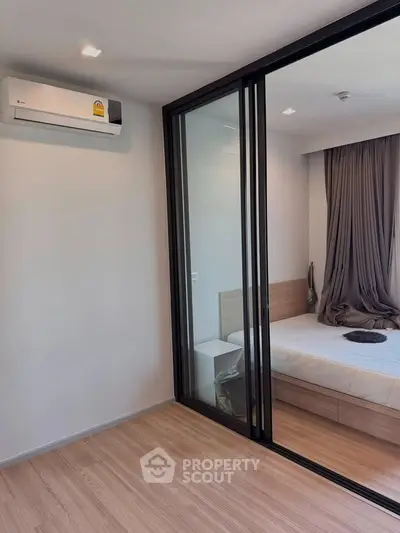 Modern bedroom with sliding glass doors and air conditioning in a stylish apartment.