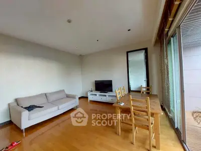 Spacious living room with wooden flooring, cozy sofa, and dining area in modern apartment.