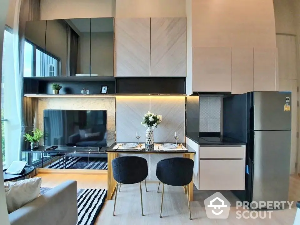 Modern living room with stylish kitchen and dining area, featuring sleek cabinetry and large windows.