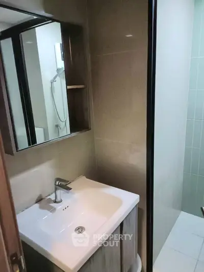 Modern bathroom with sleek sink and shower area in compact design.