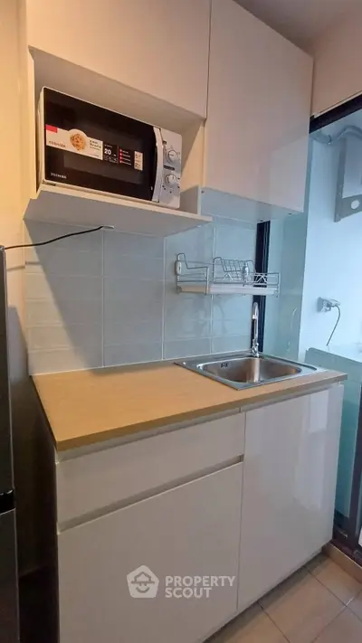 Modern compact kitchen with microwave and sleek cabinetry