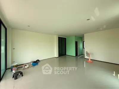 Spacious unfurnished living room with large windows and tiled flooring, perfect for customization.