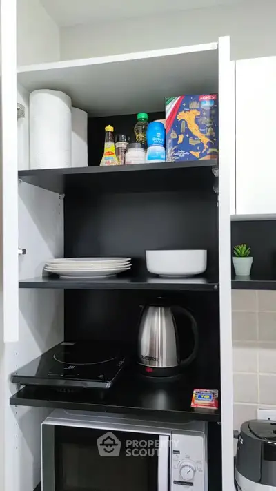 Modern kitchen with sleek black shelves, microwave, kettle, and organized storage