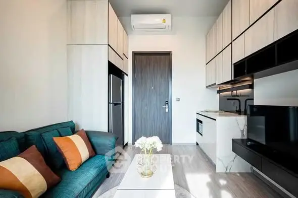 Modern living room with sleek kitchen, stylish decor, and cozy seating in a compact apartment.