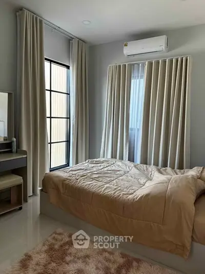 Cozy bedroom with modern decor, featuring large windows and air conditioning, perfect for relaxation.