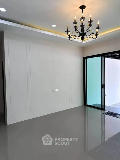 Spacious modern room with elegant chandelier and sliding glass doors